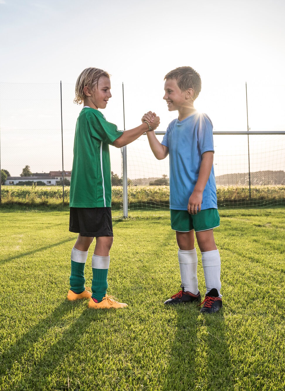 Smiling young football players shaking hands on football ground